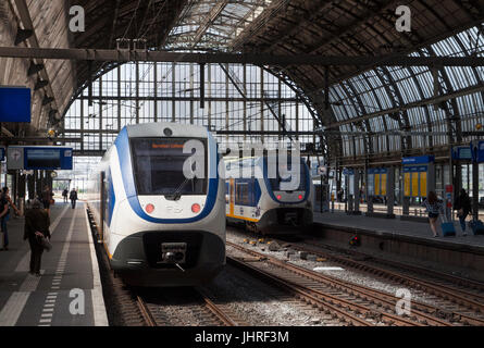 AMSTERDAM, Niederlande - Bahnhof Mai 24, 2017:Two Sprinter Züge der niederländischen Eisenbahn in Amsterdams historisches Mittel-. Und wartende Reisende Stockfoto