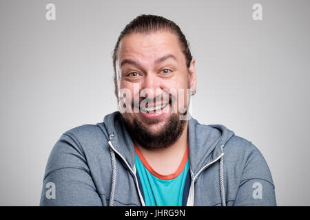 Porträt des Lachens jungen Mannes gegen graue Wand. Glücklicher Kerl Lächeln auf den Lippen. Stockfoto