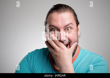 Porträt des Lachens jungen Mannes gegen graue Wand. Glücklicher Kerl Lächeln auf den Lippen. Stockfoto