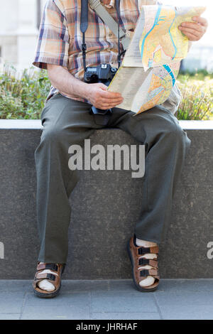 Rentner in Socken und Sandalen in Park Ziel auf Karte suchen Stockfoto