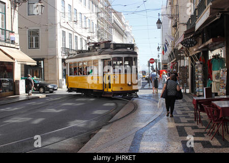 Ein Straßenbahn-Wagen Menschenmassen den Bürgersteig beim Drehen auf der Rua da Prata in der Baixa einkaufen Bezirk Lissabon Portugal Stockfoto