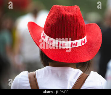 Frau das Tragen der roten Cowboy Hut mit kanadischen Flaggen für Kanada eingerichtet. Die Feier erinnert an Kanadas zum 150jährigen Jubiläum der Eidgenossenschaft. Stockfoto