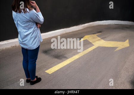 Junge Frau stand vor zwei Straßen Stockfoto