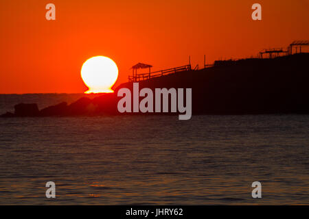 PAVILLON AM STRAND MIT DER SONNE DAHINTER Stockfoto