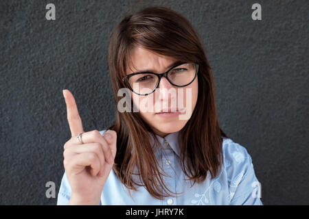 Junge schöne Mädchen in Gläsern mit ihrem Finger. Stockfoto