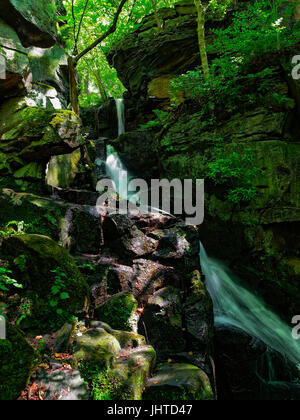 In den üppigen Wäldern der Derbyshire Dales fällt eine schmale, schnell fließende Bach einen hohen Felsvorsprung. Bewegung des Wassers ist absichtlich unscharf. Stockfoto