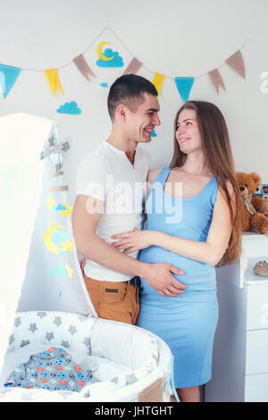 Glückliche junge Paar in Liebe stand in der Nähe ein neues Kinderbett erwartet Stockfoto