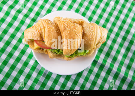 Croissant Sandwich auf einer Untertasse auf einem grünen Tischdecke Stockfoto