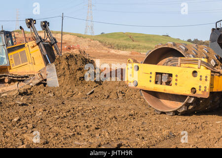 Bau Industrie Erdbau Deponie Dozer und Müllpresse Maschinenvibration Nivellierung Sand Steinen Closeup abstrakt. Stockfoto