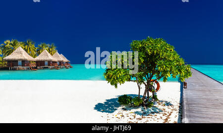 Wunderschönen tropischen Sandstrand mit Wodden Steg und über Wasser-Villen Stockfoto