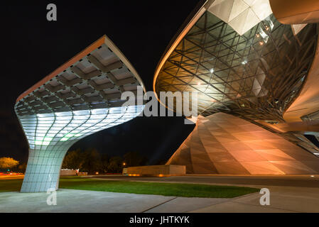 Futuristische Architektur des ein elektrisches Ladegerät für Elektro-Autos vor der beleuchteten Fassade der BMW Welt in München bei Nacht Stockfoto