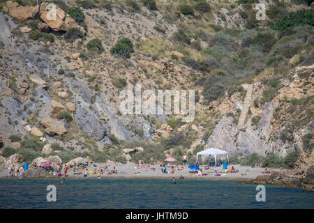 Sonnenanbeter am Strand unter den Klippen von Cala Cortina in der Nähe von Cartagena in Murcia Spanien Stockfoto