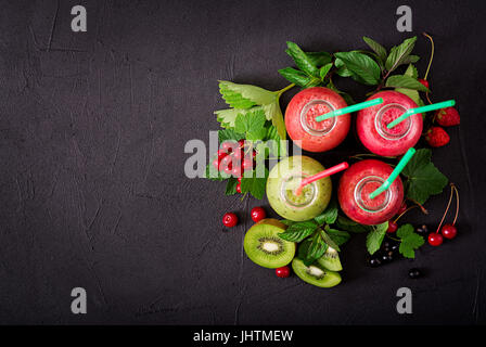 Frische gesunde Smoothies aus verschiedenen Beeren auf einem dunklen Hintergrund. Flach zu legen. Ansicht von oben. Stockfoto