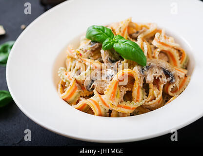 Bunte Pasta-Pappardelle mit Pilzen in Sahnesauce. Stockfoto