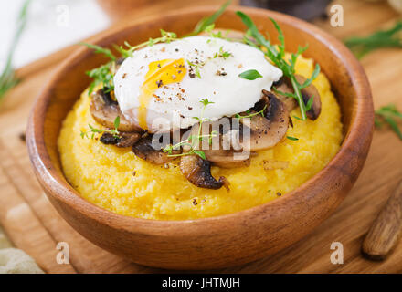 Frühstück. Polenta mit Pilzen und pochiertem Ei Stockfoto