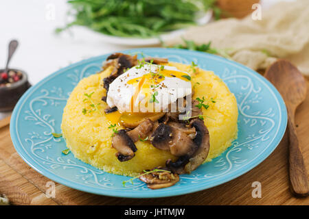 Frühstück. Polenta mit Pilzen und pochiertem Ei. Stockfoto