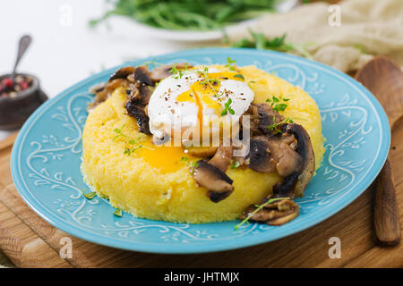 Frühstück. Polenta mit Pilzen und pochiertem Ei. Stockfoto