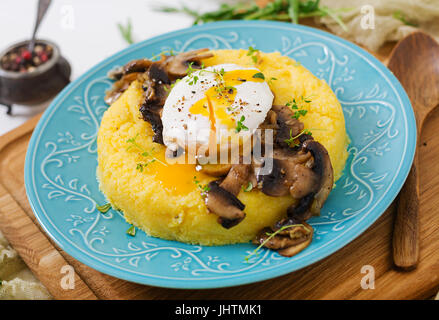 Frühstück. Polenta mit Pilzen und pochiertem Ei. Stockfoto