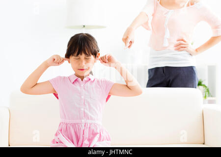 Aufgeregt Mädchen für ihre Ohren während ihre Mutter wütend Stockfoto