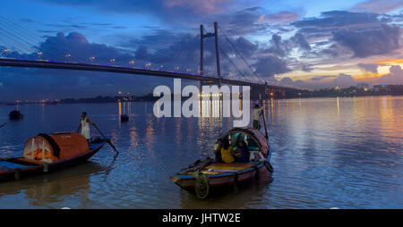 Silhouette des Vidyasagar Setu Brücke in der Dämmerung mit einem Holzboot am Hoogly River. Stockfoto