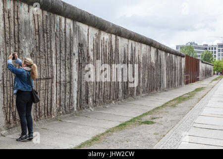 Eine Frau, die Fotos an der Berliner Mauer in Berlin macht Stockfoto