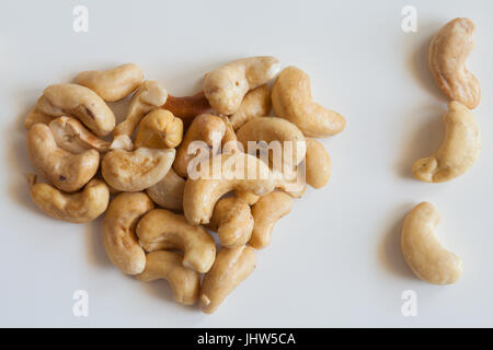 Herzförmige Haufen von Cashew-Nüssen auf weißem Hintergrund. Stockfoto