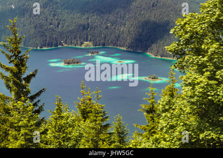 Blick auf den Eibsee zwischen Bäumen mit ein paar Inseln, Deutschland. Stockfoto