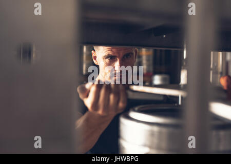 Mann in Brauerei Fabrik gearbeitet. Mitarbeiter der Produktionslinie Abfülllinie Aluminium Fass aufsetzen. Stockfoto