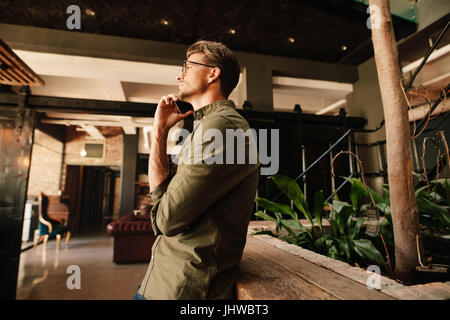 Seitenansicht des gut aussehenden jungen Mann einen Anruf tätigen. Geschäftsmann mit Handy während der Büro-Pause. Stockfoto