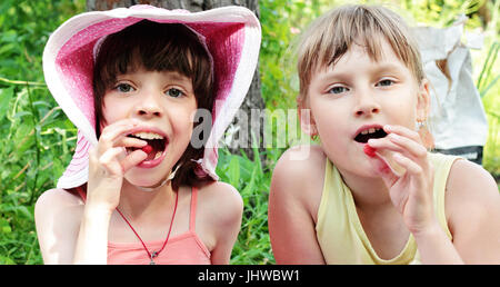 Zwei Mädchen Freundinnen Essen Himbeeren an einem sonnigen Sommertag. Stockfoto