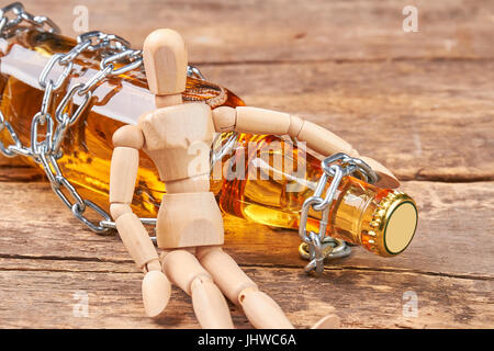 Menschlichen Holzpuppe mit Flasche sitzen. Stockfoto