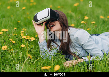 Frau mit der virtual-Reality-Kopfhörer im freien Verlegung im Frühjahr Blumenwiese Stockfoto