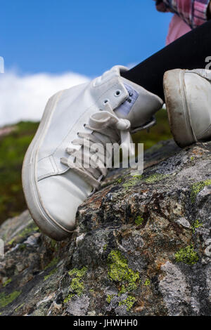 Mädchen in weißen High Tops, Teenager jugendlich Stiefel sitzen auf einem Felsen Stockfoto