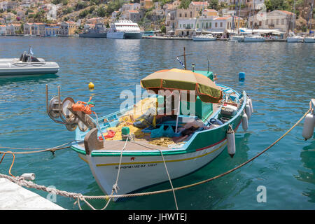 Symi-Insel, Süd Ägäis, Griechenland - ein Fischer seine Netze im Hafen von dem Hauptort ausbessern / Port, Gialos (oder Yialos, wie es auch bekannt) Stockfoto