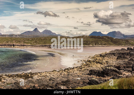 Assynt Halbinsel, Schottland - 7. Juni 2012: Achnahaird Strand ist sandig mit sanften Wellen des Atlantischen Ozeans aus Enard Bucht. Einsamer Wanderer weit am Strand. Moun Stockfoto