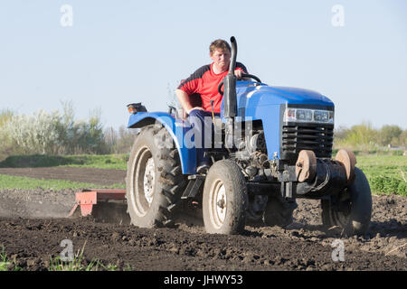 Ein Bauer auf dem Traktor landet einen Gemüsegarten im Frühjahr Stockfoto