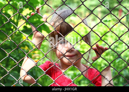 Abstraktes Bild eines kleinen Mädchens hinter Maschendrahtzaun. Foto-Kombination-Konzept Stockfoto