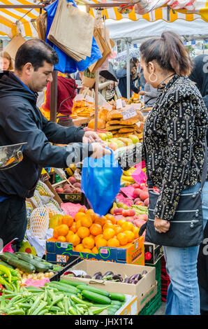 Eine Dame kauft Produkte Form einen Obst und Gemüse Stand auf der Portobello Road in Notting Hill, London. Stockfoto