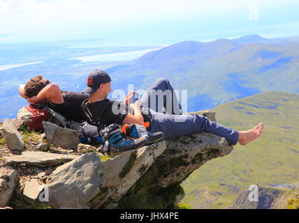 Zwei männliche Wanderer ruht auf Felsen Überhang, Mount Snowdon, Gwynedd, Snowdonia, Nord-Wales, UK Stockfoto