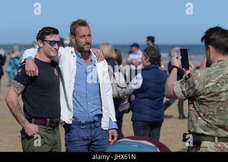 TV-Moderator Ben Fogle posiert für ein Foto mit einem Mitglied des montiert-Kavallerieregiments Haushalt wie sie ihre Pferde im Meer trainieren, nehmen sie Teil an der jährlichen Regimental Ausbildung am Holkham Beach in Norfolk. Stockfoto