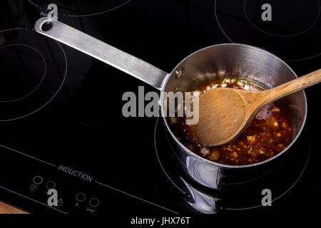 Topf mit CombineObject weißen Zucker auf ein Induktions-Kochfeld Stockfoto