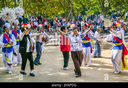 Republik Korea, Suwon, Korean Folk Village, Touristen an einen Bauern Tanz teilnehmen Stockfoto