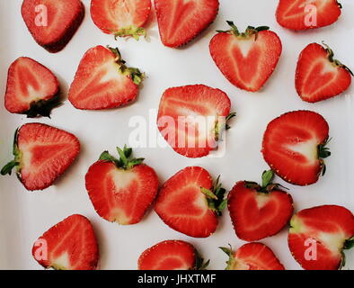 Erdbeer-kreative Muster. Isolierte Essen Kulisse. In Scheiben geschnitten Reife rote Beeren mit grünen Blättern auf weißem Hintergrund Stockfoto