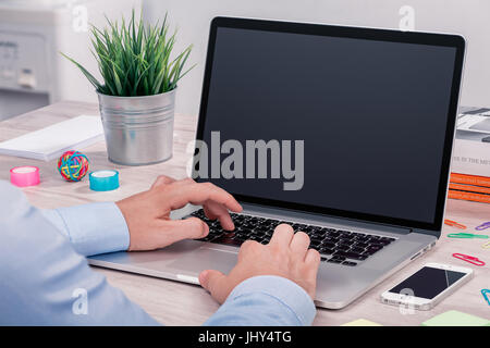 Mann mit Laptop arbeiten. Mans Hände auf Laptop-Computer. Geschäftsmann am Arbeitsplatz Texteingabe auf Laptop mit leeren Bildschirm Mock-up. Stockfoto