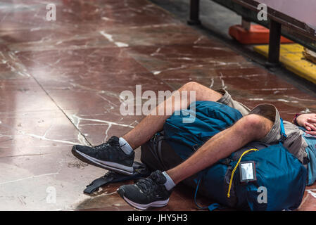 Ein Junge schläft in einem Bahnhof wartet auf seinen Zug Stockfoto