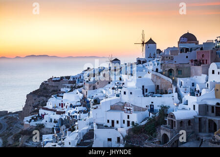 Blick auf den Sonnenuntergang über den weiß getünchten Gebäuden und Windmühlen von Oia aus dem Schloss Wände, Santorin, Kykladen, Griechenland Stockfoto