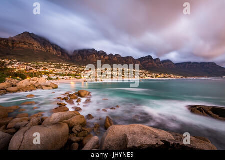 Langzeitbelichtung bei Sonnenuntergang in Camps Bay mit Wolke über dem Tafelberg und den zwölf Aposteln, Cape Town, Südafrika, Afrika Stockfoto