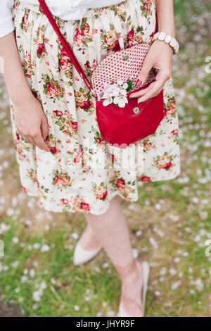 Elegantes Outfit. Nahaufnahme von roten gesteppte Leder Tasche Handtasche in Händen der stilvolle Frau. Modische Mädchen auf der Straße. Sonniger Tag. Weibliche Mode conce Stockfoto