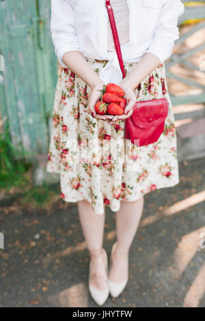 Frau im Kleid hält eine Reihe von Erdbeeren. Stockfoto