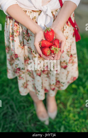 Frau im Kleid hält eine Reihe von Erdbeeren. Stockfoto